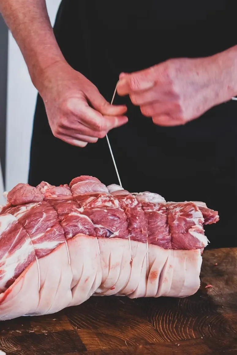 A butcher tying a joint at the block